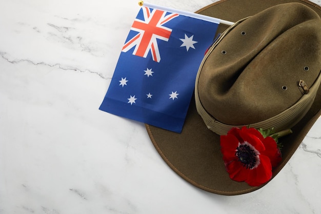 Chapéu desleixado do exército Anzac com bandeira australiana e papoula em fundo de pedra