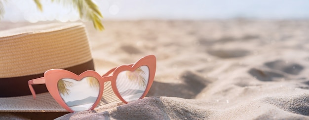 Chapéu e óculos de sol na praia de areia tropical com espaço de cópia, conceito de férias de verão