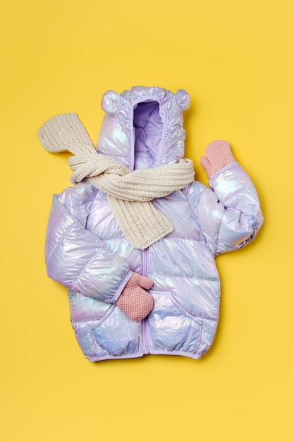 Chaqueta acolchada para niños con capucha sobre fondo rosa. Prendas de abrigo para niños con estilo. Traje de moda de invierno