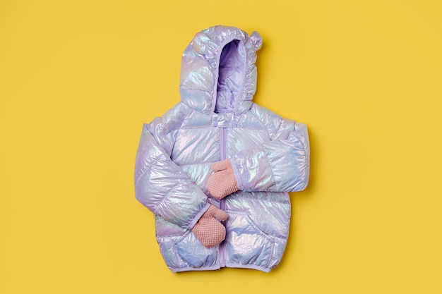 Chaqueta acolchada para niños con capucha sobre fondo rosa. Prendas de abrigo para niños con estilo. Traje de moda de invierno