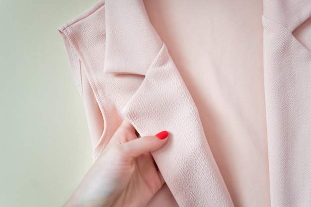 Chaqueta de cuello rosa en una mano femenina. Detalles De moda