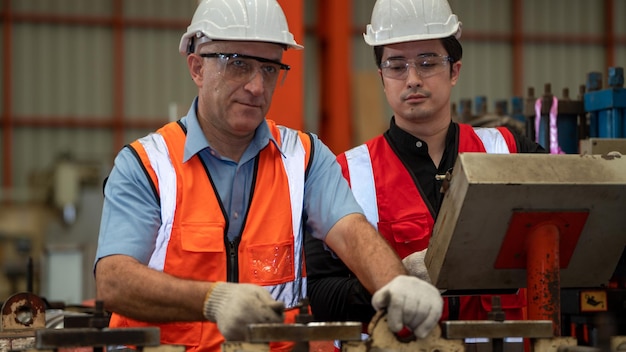 Chaqueta de seguridad de dos ingenieros de capataz de la industria pesada Máquina de verificación de mantenimiento preventivo diario en la fábrica de fabricación Uso de Labtop Discusión Capacitación Habilidades Calidad de mantenimiento