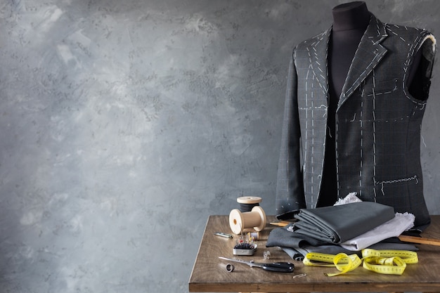 Chaqueta de traje en maniquí de sastre masculino y herramientas de costura, concepto creativo de taller de ropa