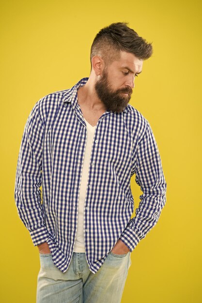 Charismatischer Mann mit Bart auf gelbem Hintergrund Männliche Mode und Frühlingsstil Reifer ernsthafter Mann Sommer-Hipster Brutaler bärtiger Hipster im karierten Hemd männlicher Bartstil trendiger Mann