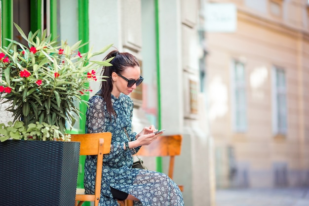 Charla de la mujer por su teléfono inteligente en la ciudad. Turista atractivo joven al aire libre en ciudad italiana