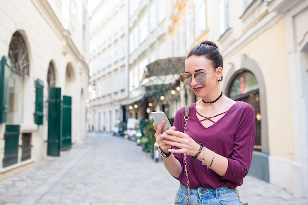 Charla de la mujer por su teléfono inteligente en la ciudad.