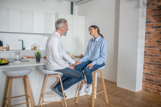 Charlas en la cocina. Un hombre y una mujer sentados en la cocina y hablando.