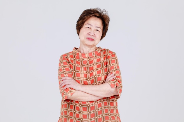 Charmante ältere Chinesin sieht gesund und fröhlich aus auf lässigem Stoffhemd mit kariertem Muster als älteres elegantes Kostüm für freundliche Mutter. Oma sieht glücklich aus und entspannt sich für einen positiven Lebensstil.