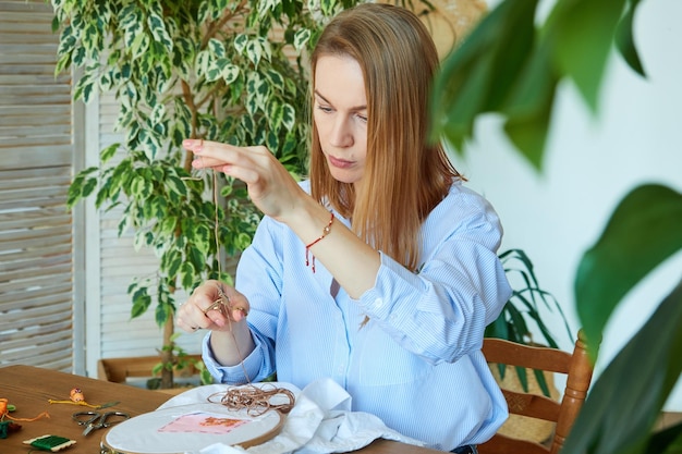 Charmante blonde Stickerin verwendet Schere das Konzept der Kreativität Handarbeit