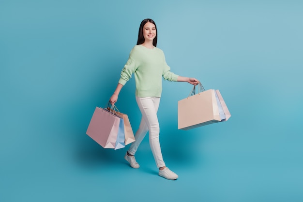Charmante Dame trägt Einkaufstüten isoliert auf blauem Hintergrund