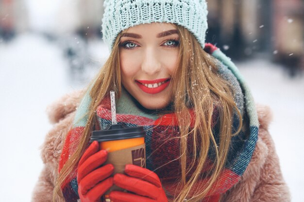 Charmante Frau mit roten Lippen hält Tasse Kaffee in ihre Arme