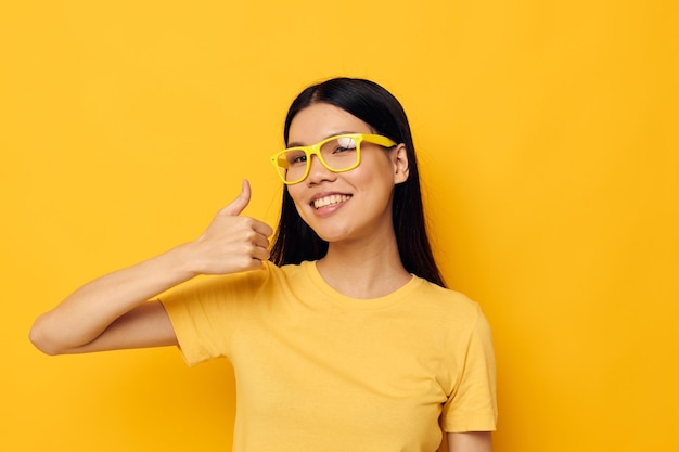 Charmante junge asiatische Frau in gelben T-Shirts mit Brille posiert Mode Lifestyle unverändert