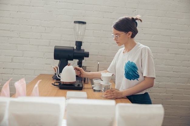 Charmante junge Frau, die Filterkaffee in der Cafeteria macht