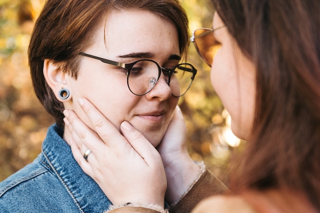 Charmante junge Frauen, die sich sanft küssen und sich streicheln und die berührende Gesichtshaut streicheln, genießen romantische zarte Momente beim Picknicktermin auf dem Land.