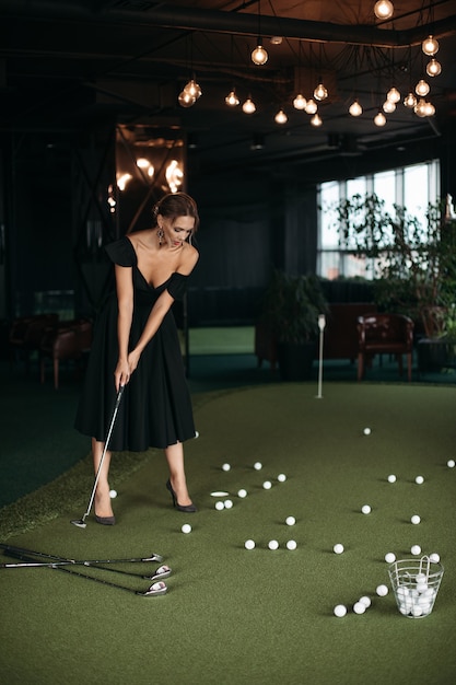 Charmante kaukasische Dame posiert für die Kamera und spielt Golf, Bild einzeln auf dunklem Hintergrundunschärfe