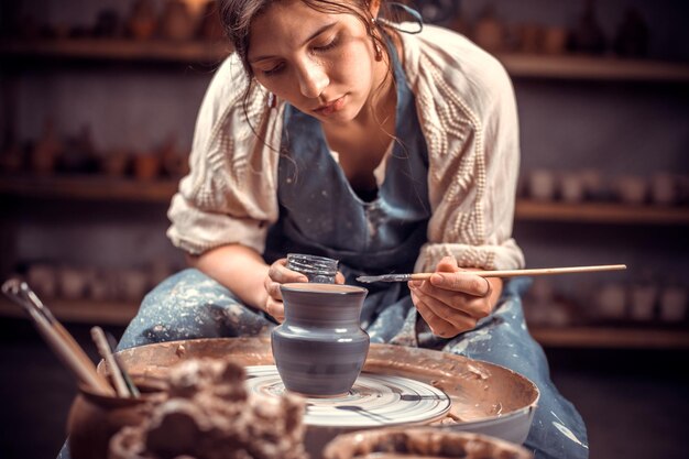 Charmante Keramikerin, die mit rohem Ton mit den Händen an der Töpferscheibe arbeitet. Handwerk.