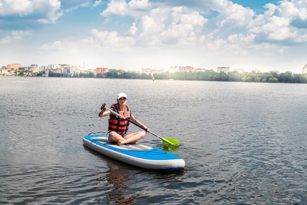 Charmante lächelnde Frau reitet auf einem Sup-Paddle-Board um den aktiven Lifestyle-Sport und die Gesundheit des Stadtsees