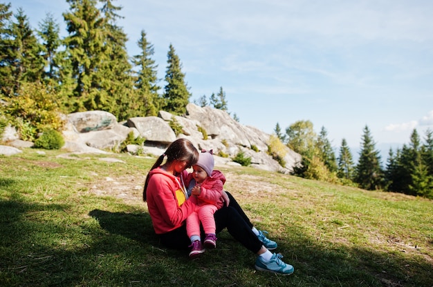 Charmante Mutterliebe. Mutter mit Tochter sitzen auf Bergen gegen Steinfelsen.