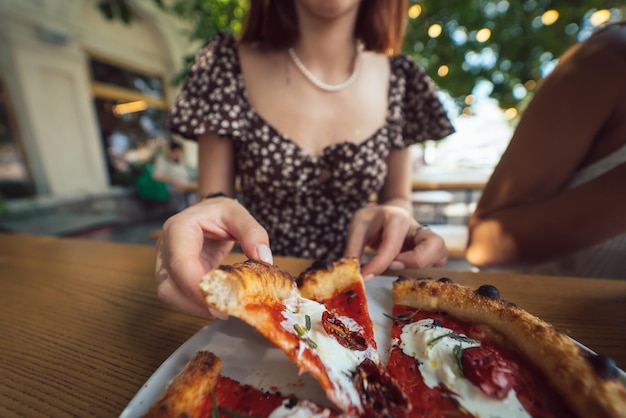 Charmante schöne Frau nimmt ein Stück Pizza