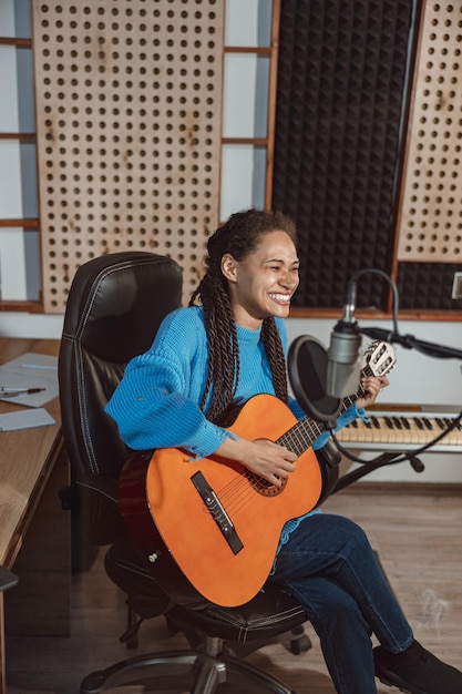 Charmante talentierte afrikanische junge Musikerin, Songwriterin, Sängerin, spielt Gitarre und nimmt im Musikstudio neue Songs auf