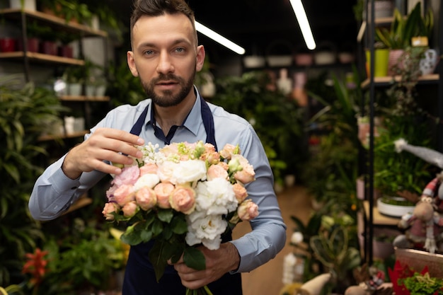 Charmanter männlicher Florist mit einem Blumenstrauß in den Händen zum internationalen Frauentag