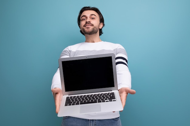 Charmanter, positiver Mann im roten Hemd, der den Laptop-Bildschirm nach vorne hält