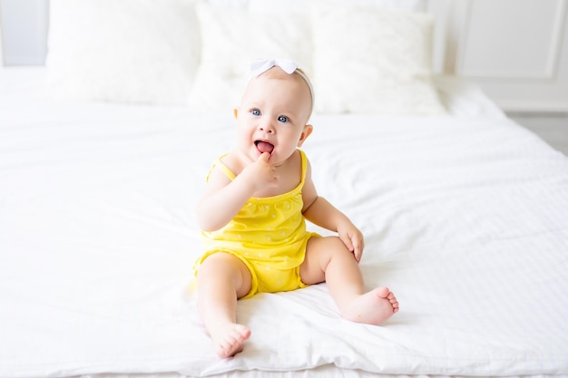 Charmantes Babymädchen in einem weißen, sonnigen Schlafzimmer Ein neugeborenes Baby ruht im Bett