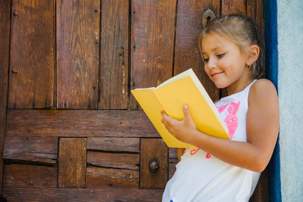 Charmantes Kind liest Buch auf Veranda