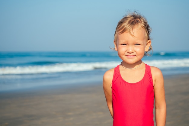 Charmantes kleines Mädchen, das am Strand lächelt und sich sonnt