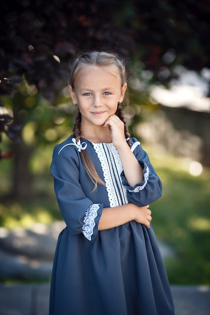 Charmantes kleines Mädchen in einem Retro-Kleid, das in der Stadt an einem sonnigen Sommertag geht. Kleines Mädchen tragen Schuluniform.