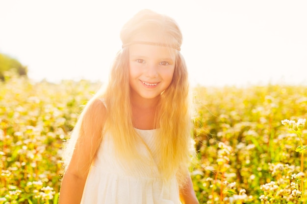 Charmantes kleines Mädchen in einem weißen Kleid Stilvolles Kind mit langen blonden Haaren auf einem Hintergrund von Sonnenlicht