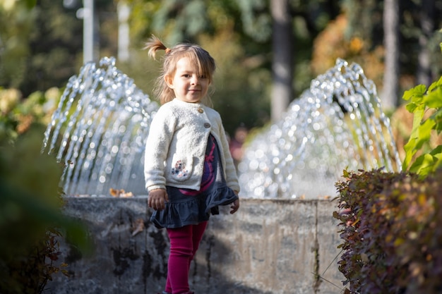 charmantes Kleinkind im Park mit Springbrunnen im Hintergrund. Sommertag