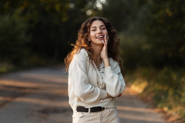 Foto charmantes mädchen mit lockigem haar und weißem lächeln in einem modischen herbstpullover