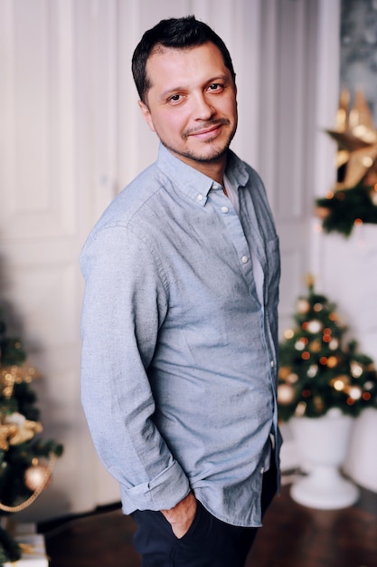 Foto charming lächelnder mann neben einem weihnachtsbaum