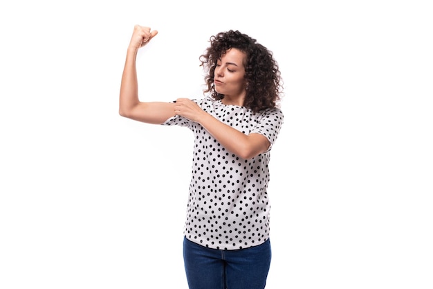 Charmosa jovem morena mulher encaracolada vestida com uma blusa de verão com uma impressão de ervilha ativamente