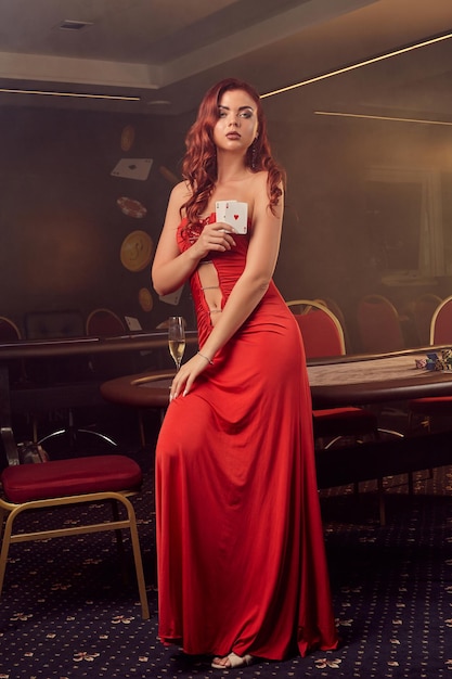 Charnimg mujer sexy está posando contra una mesa de póquer en el casino de lujo