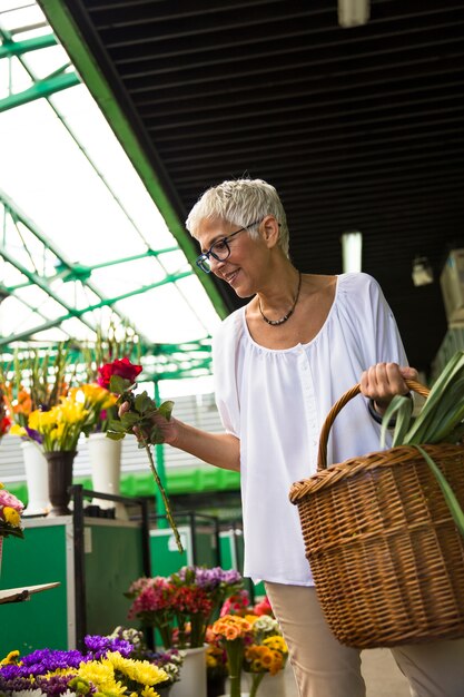 Charrming mulher sênior comprar flores no mercado