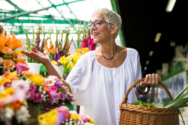 Charrming mulher sênior comprar flores no mercado