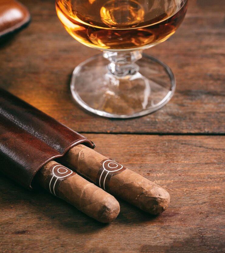 Foto charutos cubanos e snifter com rum na mesa de madeira