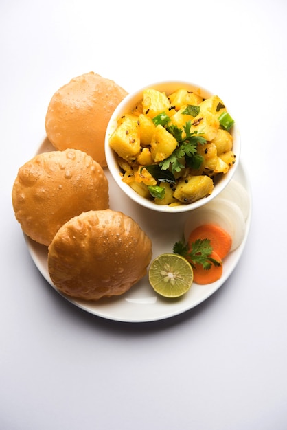 Chatpate Masala Aloo Sabzi Fry ODER Bombay Kartoffeln serviert mit gebratenem Puri oder indischem Brot aus Weizen in einem Teller, selektiver Fokus