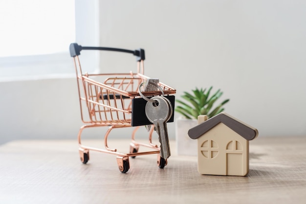 Chave de casa no carrinho de compras com casa modelo na mesa de escritório. Compra, venda e aluguel de casas e p