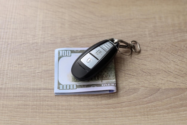 Chave do carro e dólar americano na mesa de madeira. Conceito de finanças e seguros.