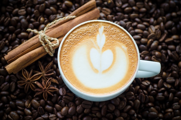 Chávena de café com arte latte em fundo de feijão de café