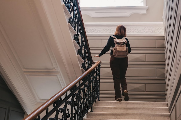 Check-in no hotel de um viajante com uma mochila A mulher sobe as escadas cópia espaço