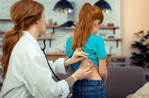 Check up médico. Jovem simpática em frente ao médico durante um exame médico