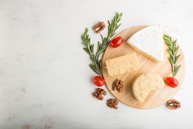 Cheddar und verschiedene Arten von Käse auf Holzbrett auf weißem Hintergrund