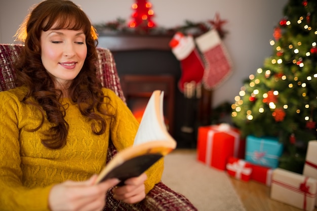 Cheerful cabelo vermelho lendo um livro no natal