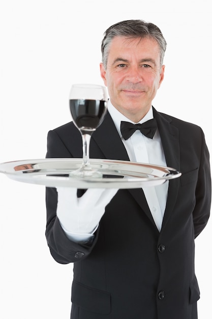 Foto cheerful garçom segurando um copo de vinho em uma bandeja de prata