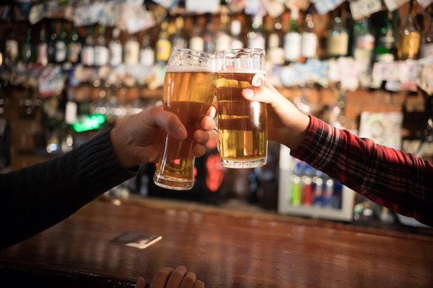 Cheers closeup de dois homens brindando com cerveja no balcão do bar