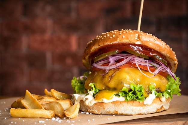 Cheese Beef Burger mit Gemüse und Pommes auf Holzbrett